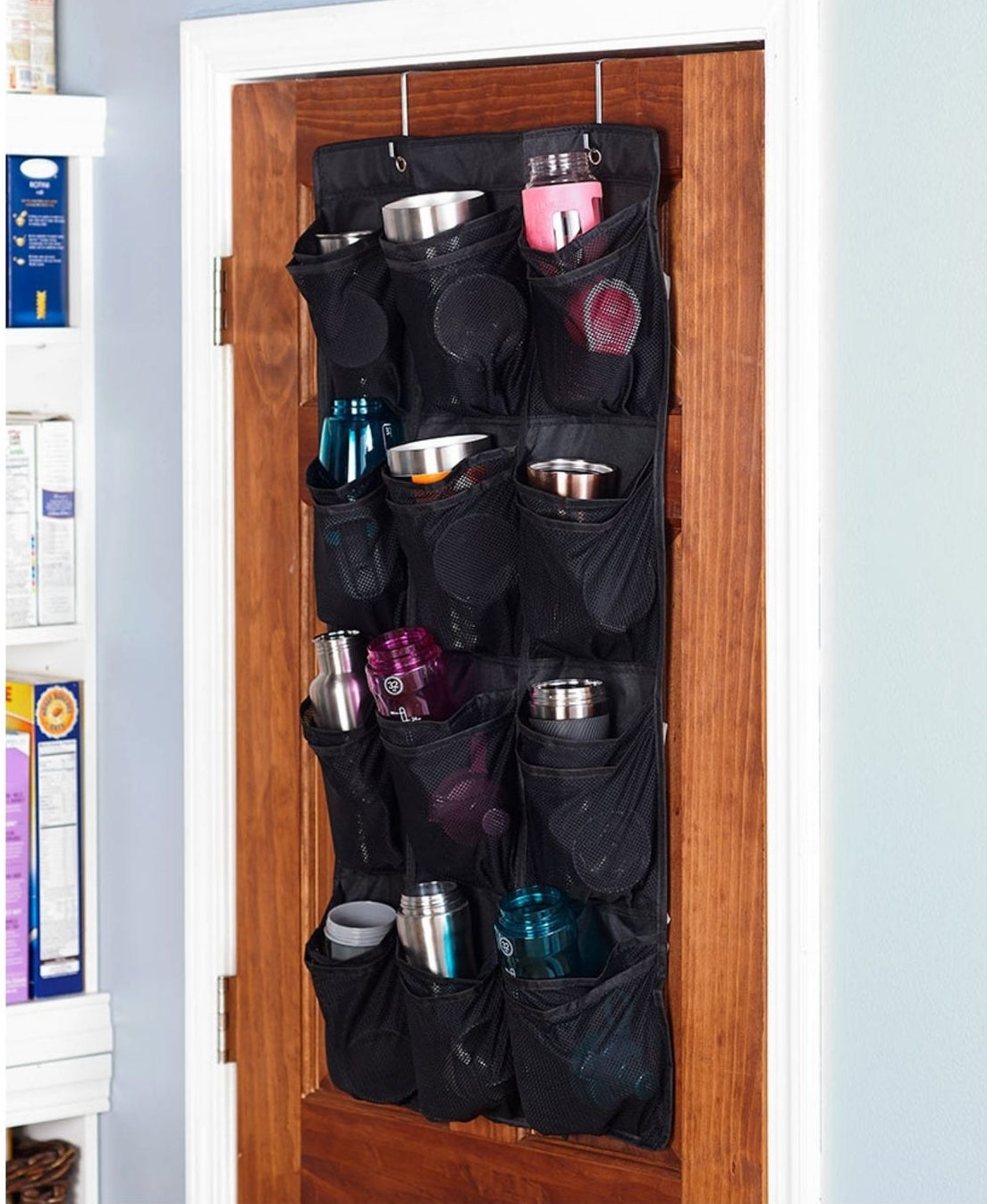The water bottle organizer hanging on a pantry door