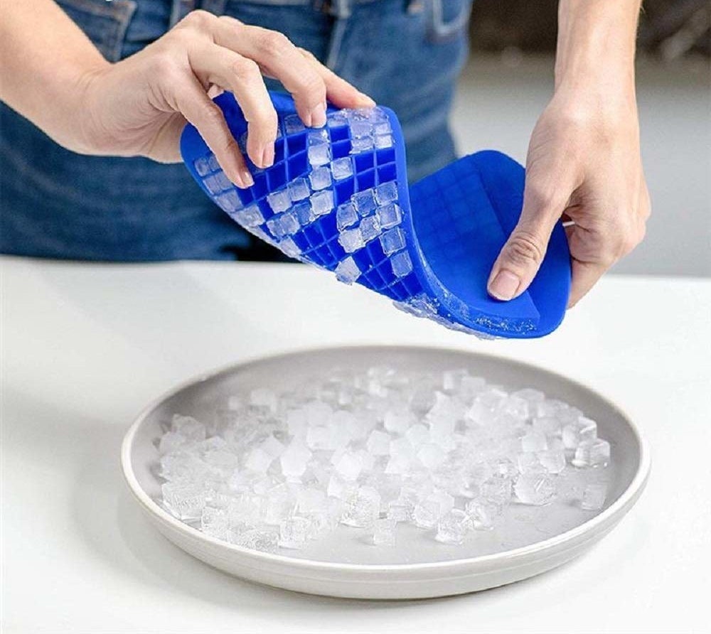 A person removing ice into a plate from the silicone tray