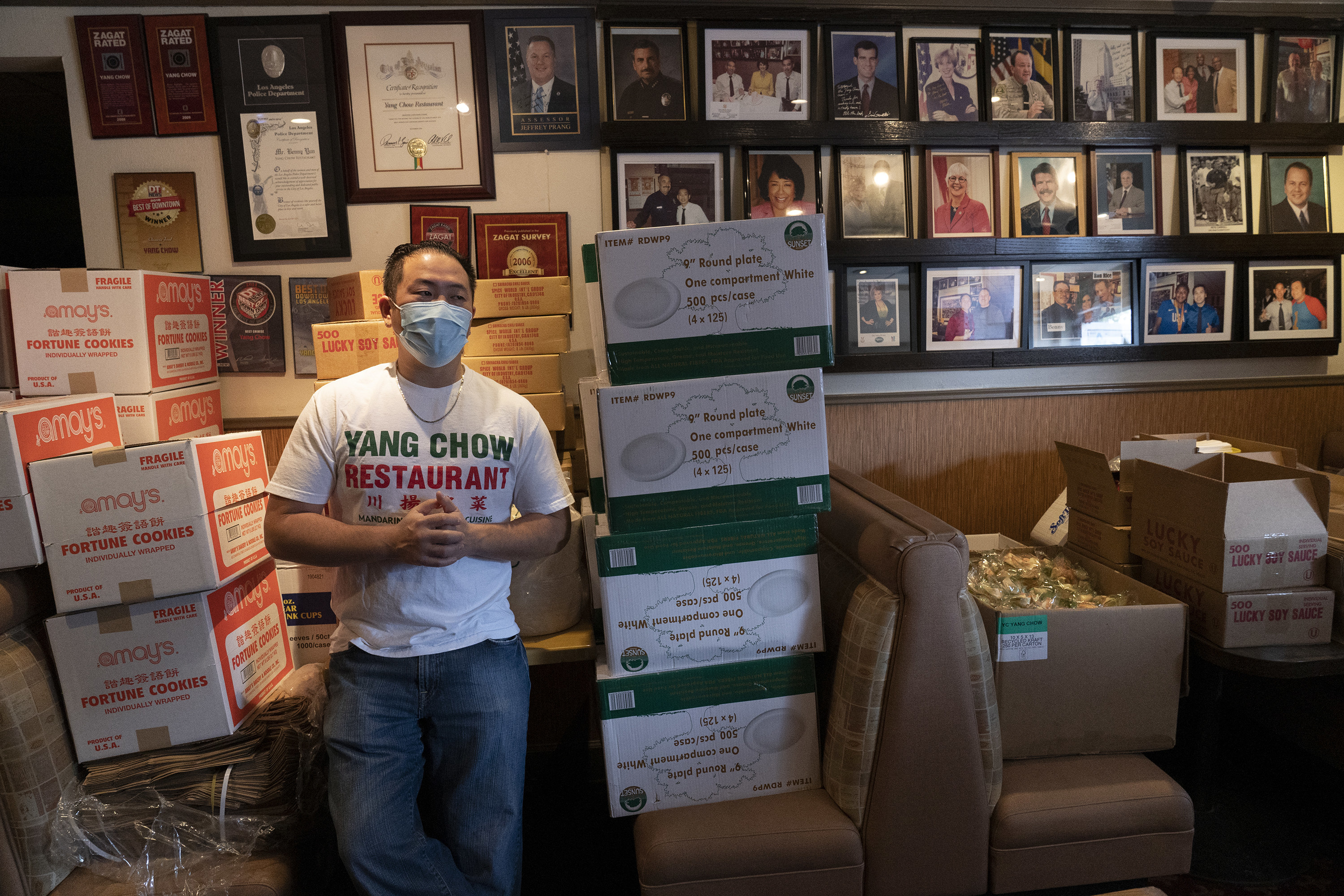 A man stands in his restaurant with unopened boxes of plates and fortune cookies