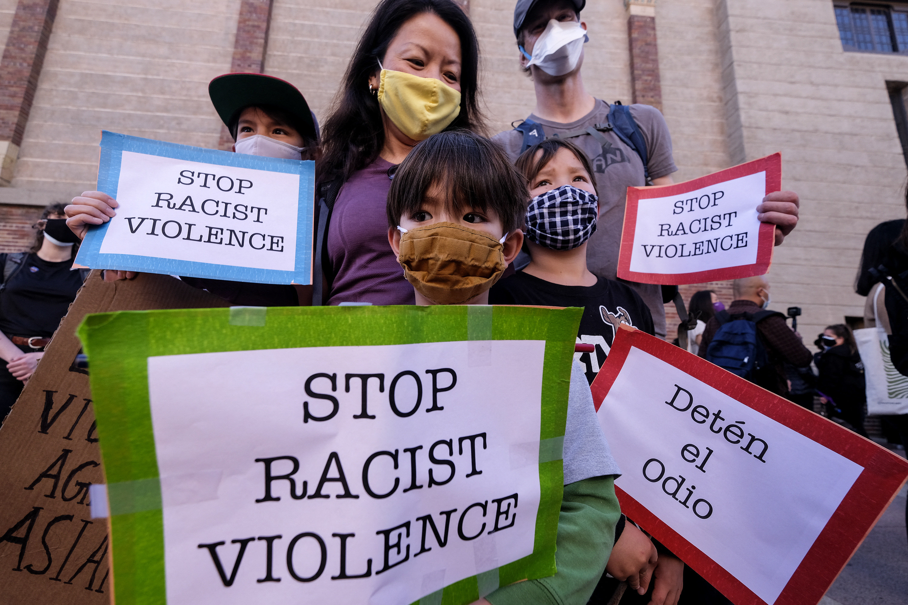 Family members wear face masks and hold signs that read &quot;Stop Racist Violence&quot;