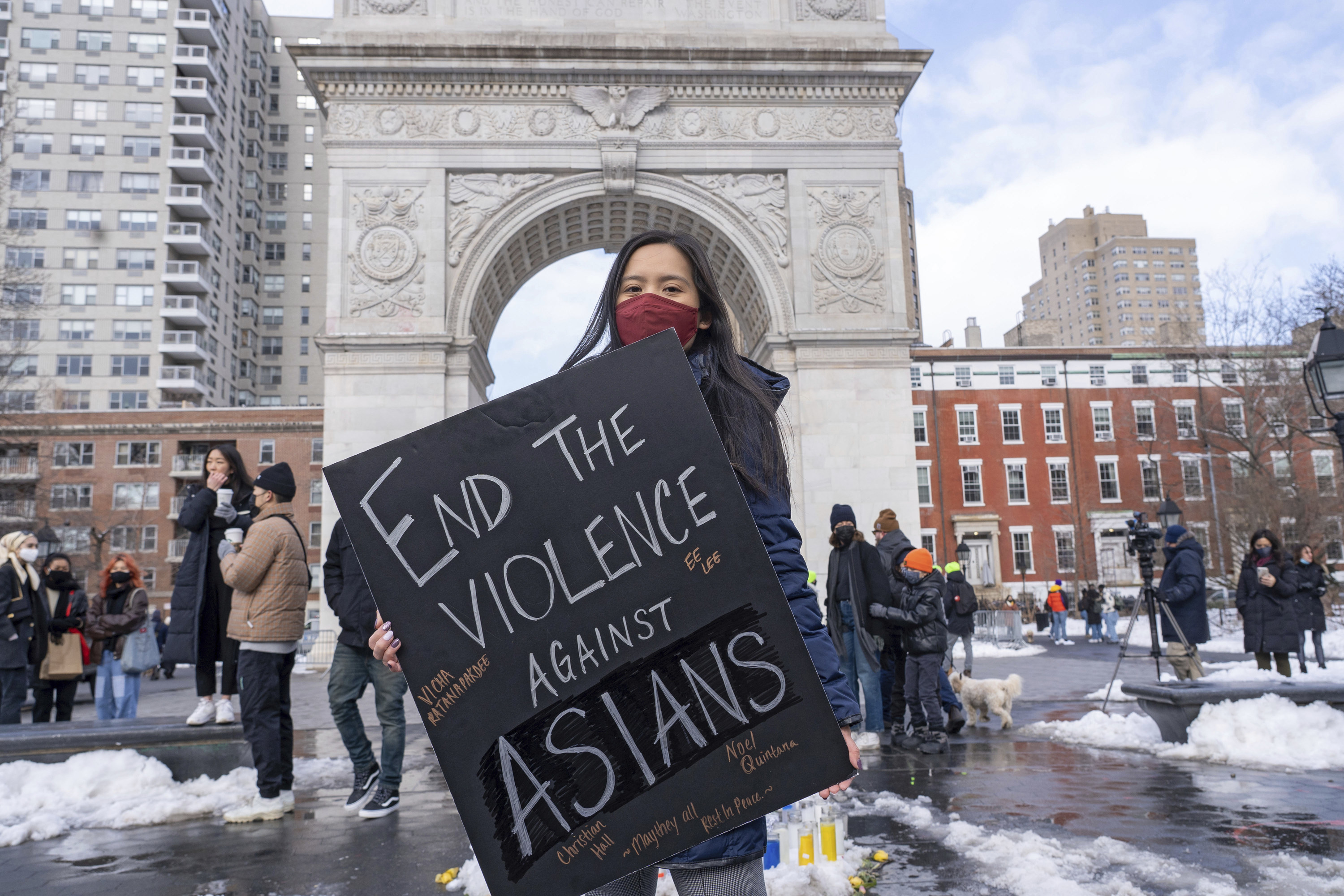 A protester holds a placard that reads &quot;end the violence against Asians&quot; in front of the Washington Square Arch surrounded by snow on the ground