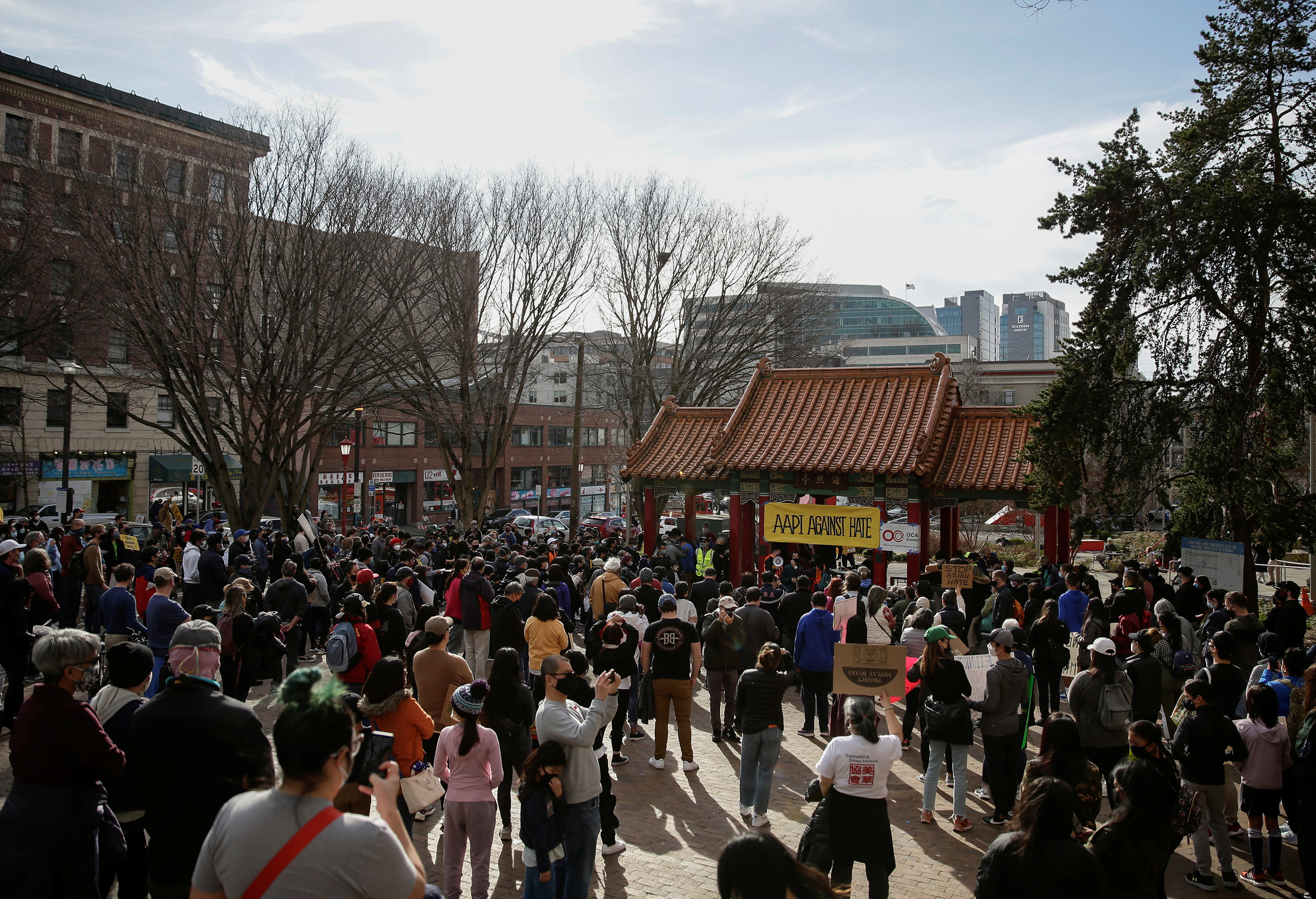 Hundreds of people gather in Seattle&#x27;s Chinatown to protest; in the background, a sign reads &quot;AAPI against hate&quot;