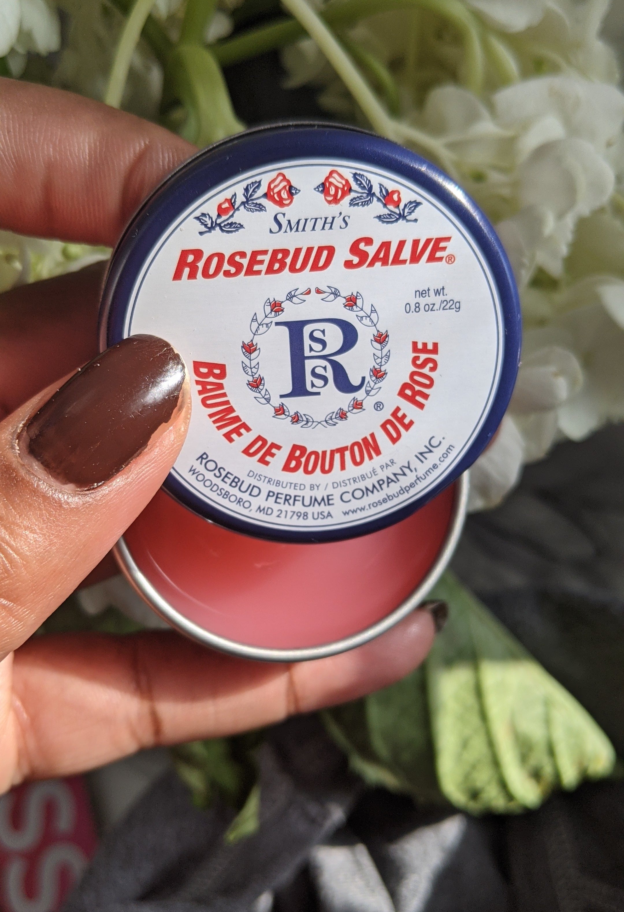 A person&#x27;s hand holding a small tin of lip salve