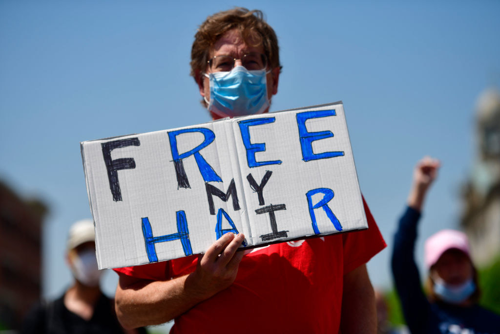 Person holding a sign reading, "Free my hair"