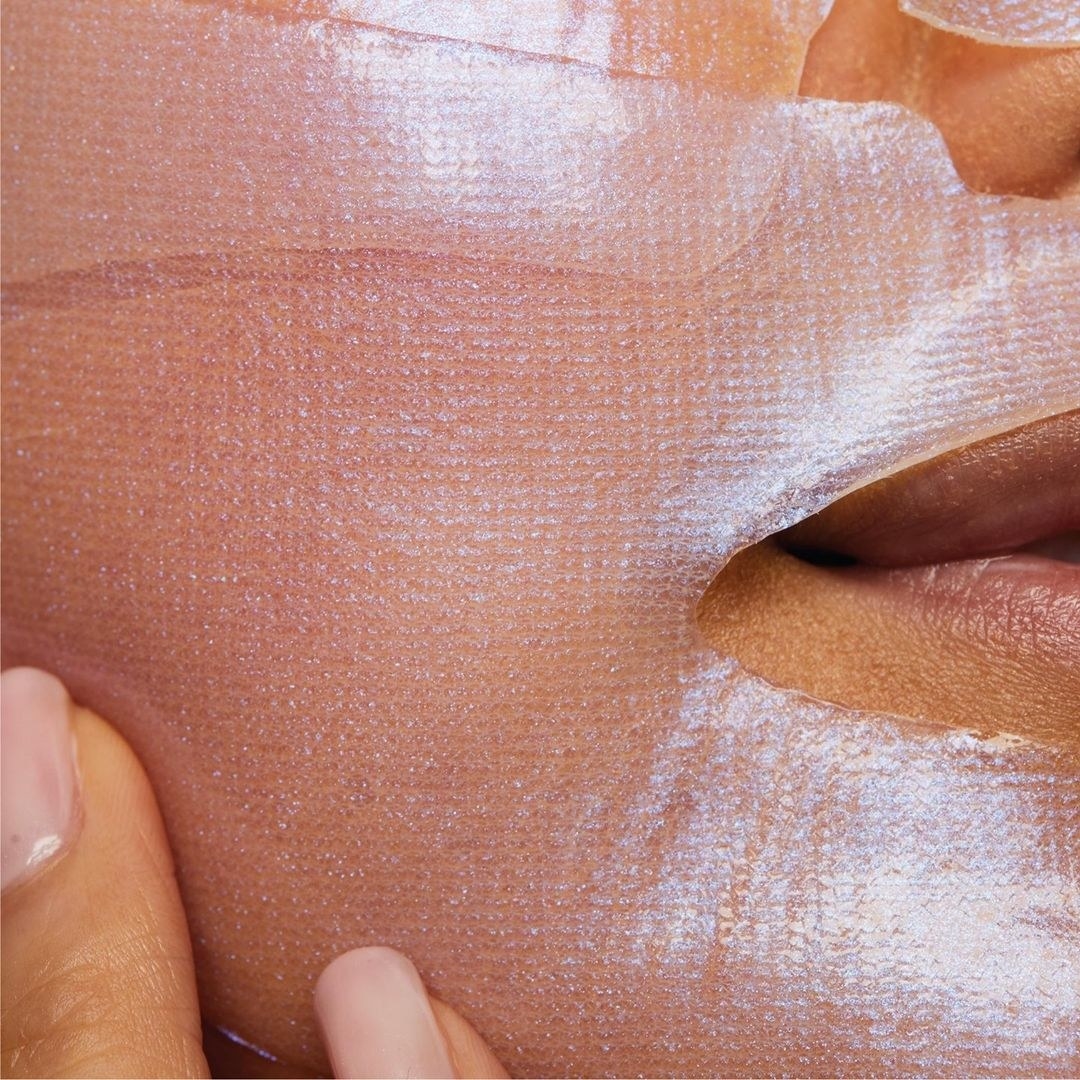 A close up of a shimmering hydrogel sheet mask on someone&#x27;s face