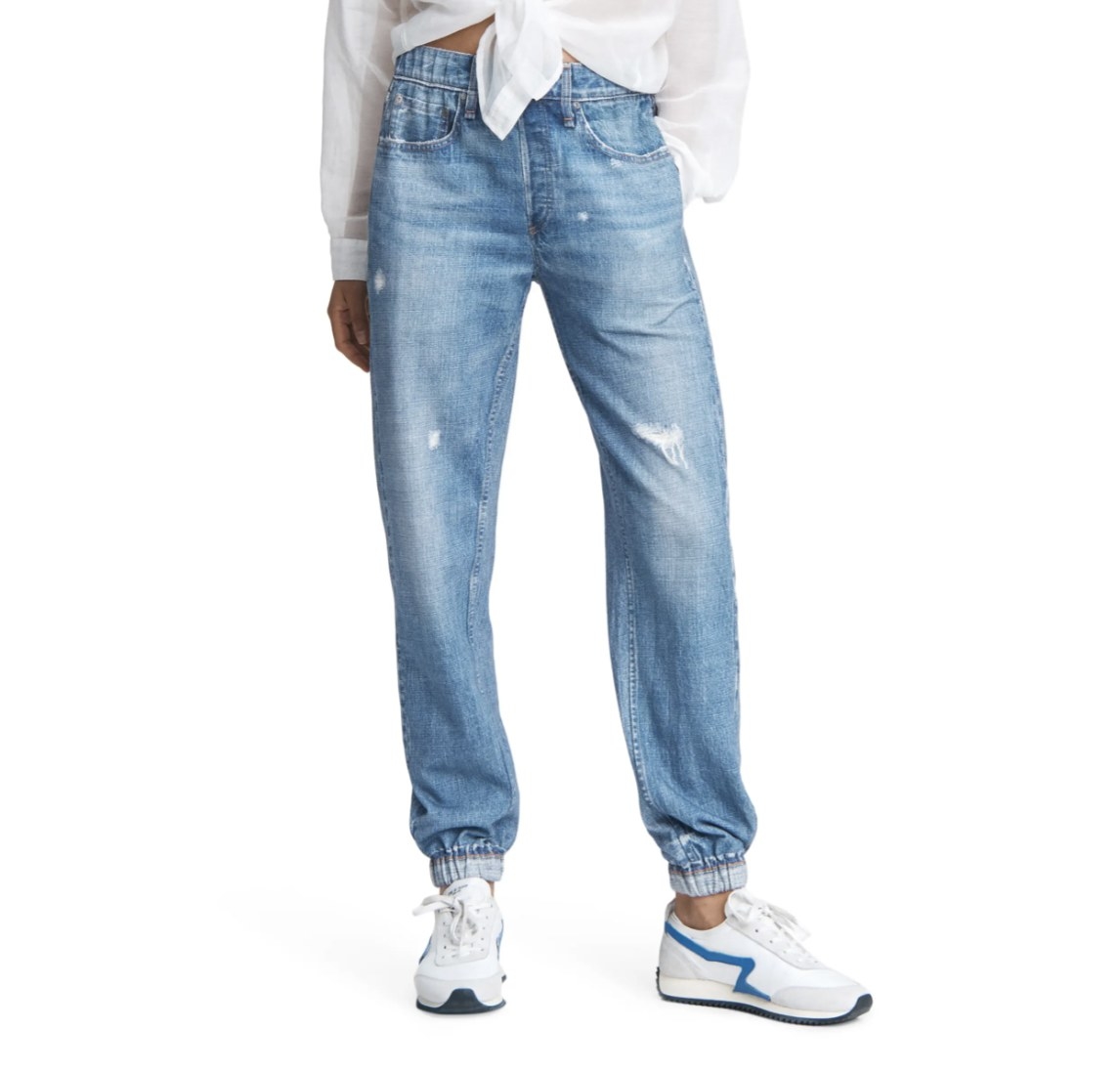 Model is wearing denim joggers and white sneakers