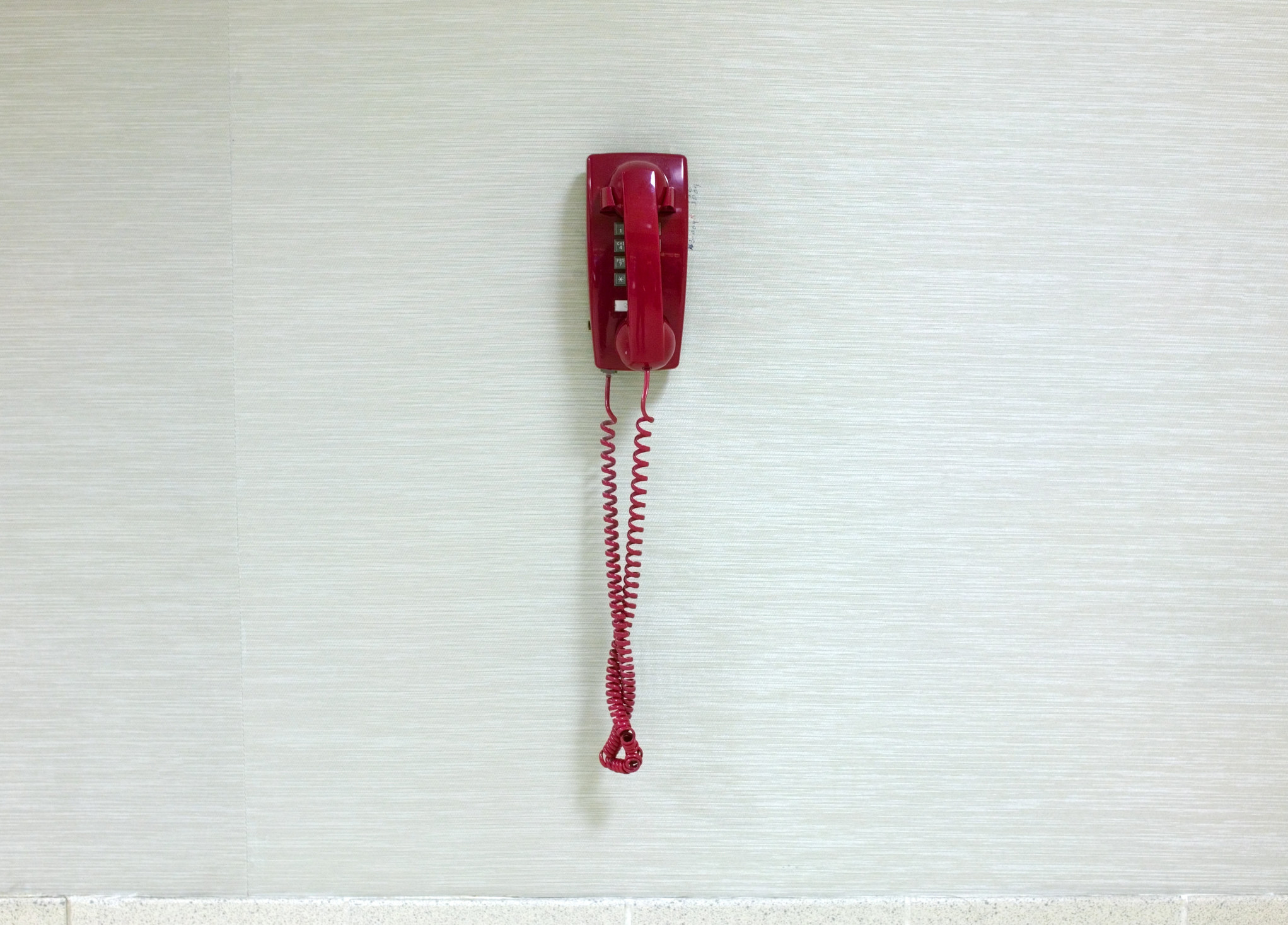 A red telephone on a white wall