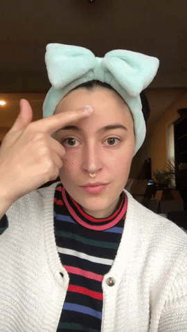 gif of a buzzfeed editor applying the lotion to their face
