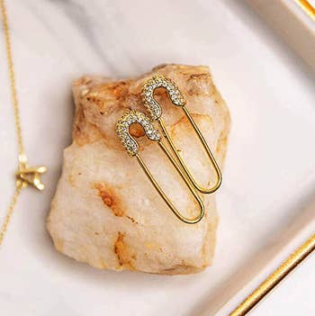 closeup of safety-pin style earrings styled on a crystal