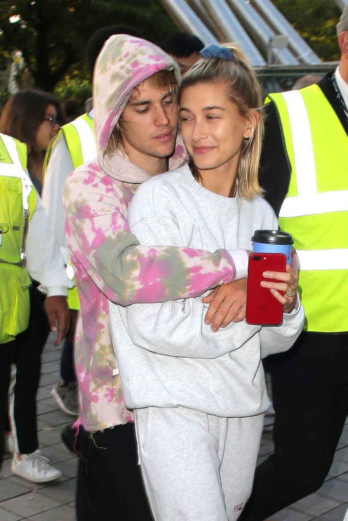 Justin hugging Hailey from behind as she smiles at him