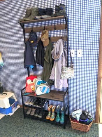 storage rack and coat hooks combo with clothes and shoes on it