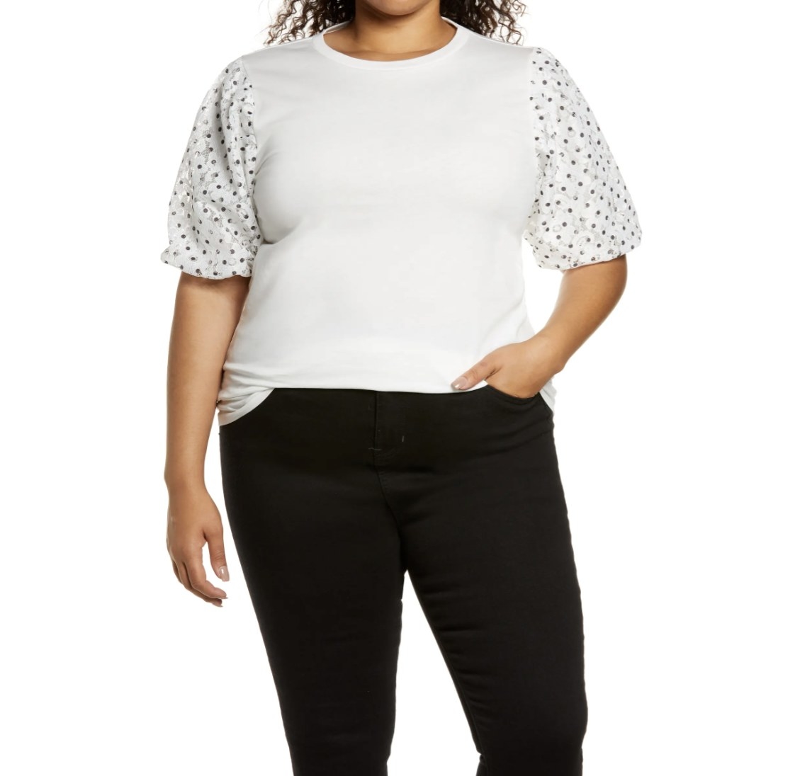Model is wearing a white top with polka dot sleeves and black pants