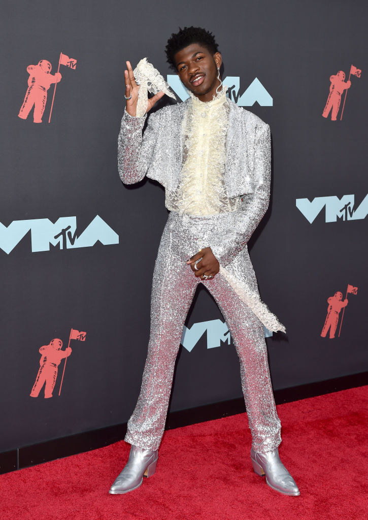 Lil Nas X posing at the VMAs in a sparkly suit and ruffled shirt