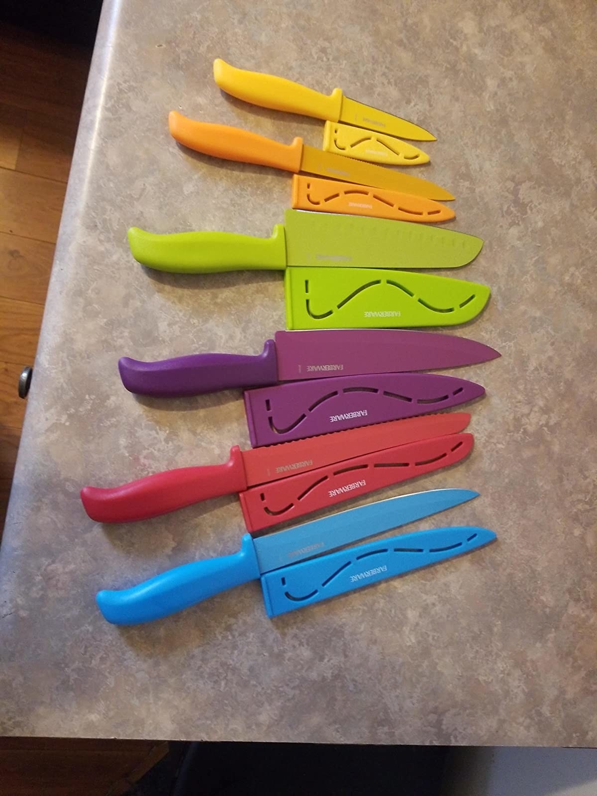 The six knives, each of which are a different bright color, and their corresponding covers