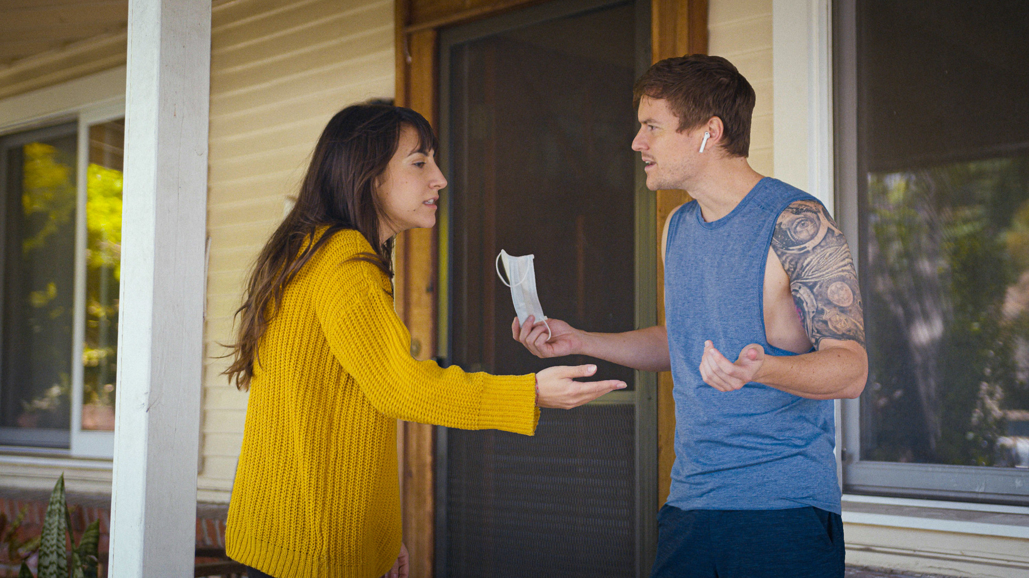 A couple arguing by the front door of a house