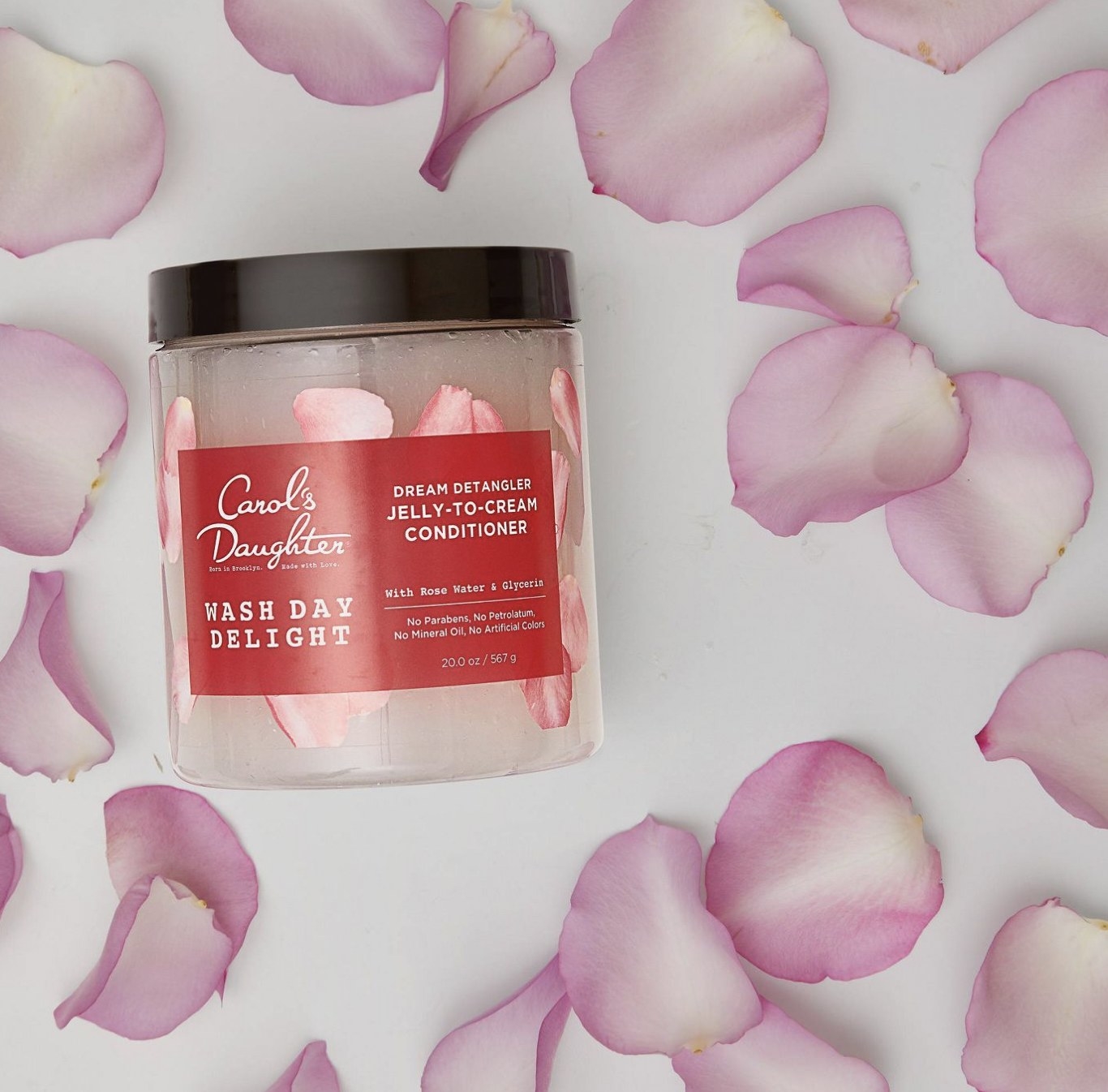 A jar of conditioner surrounded by rose petals