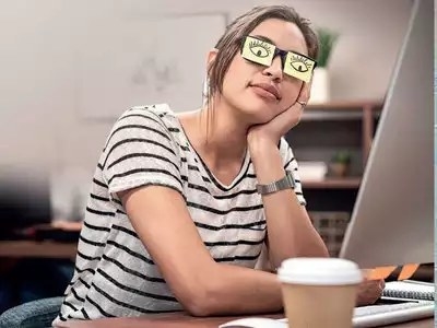 Woman asleep at desk pretending to be awake with fake eyes drawn onto paper. 