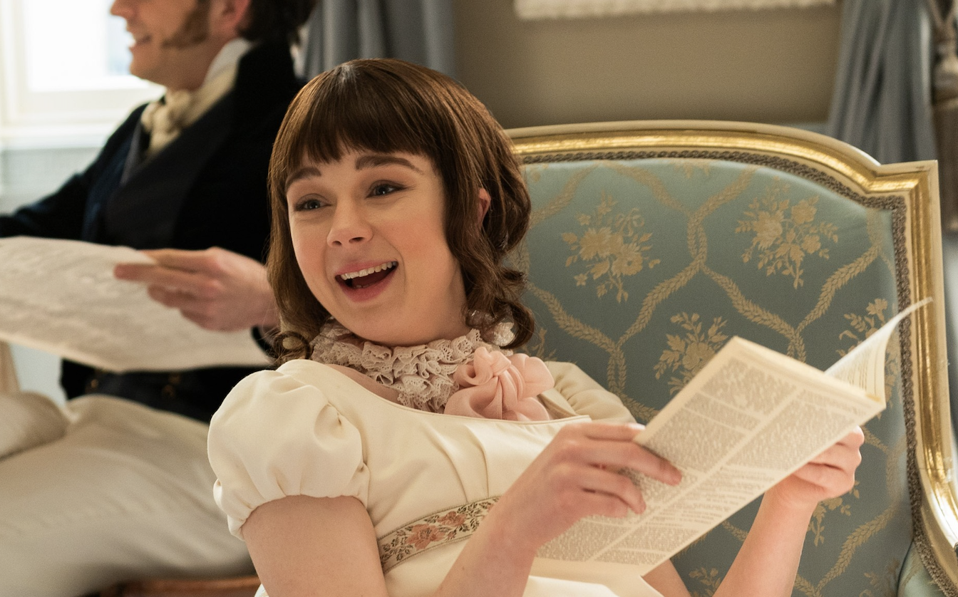 Eloise smiling and holding the gossip column in her hands