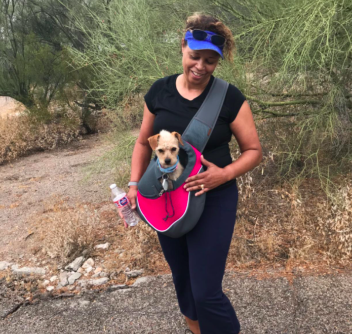 Reviewer walking with small dog in the sling pouch