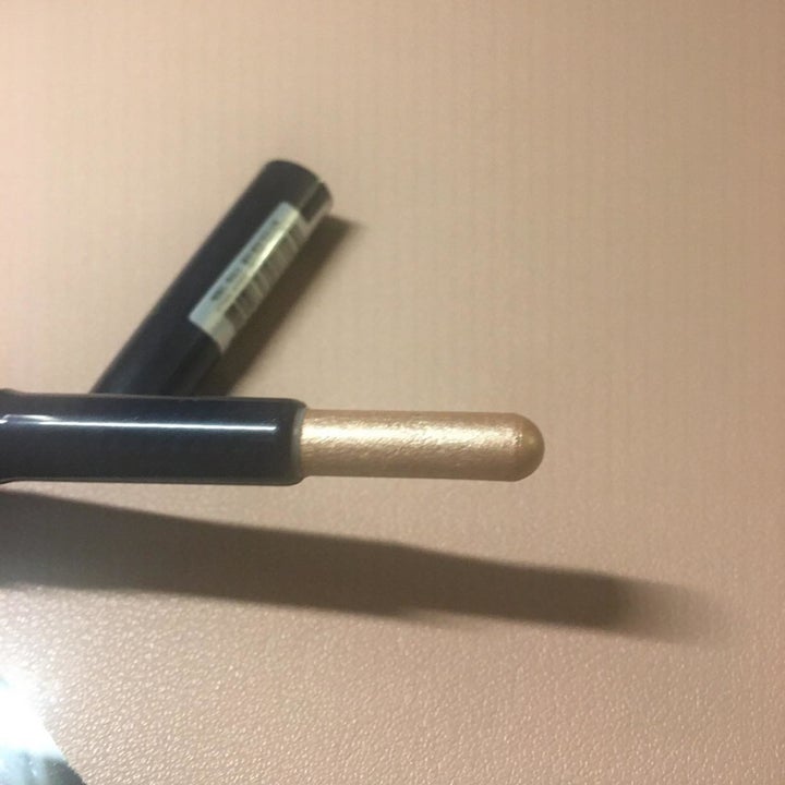 reviewer showing the rounded nub and the entire gold stick lifted up from inside the tube