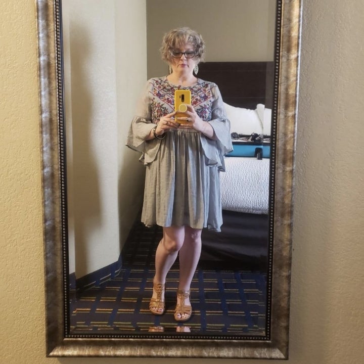 a reviewer wearing the embroidered dress in gray