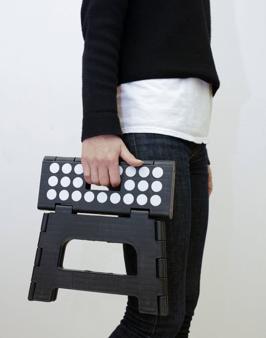 model holding black and white foldable step stool