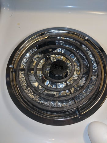 Reviewer photo of Electric Stove Bib Liner placed in drip pan