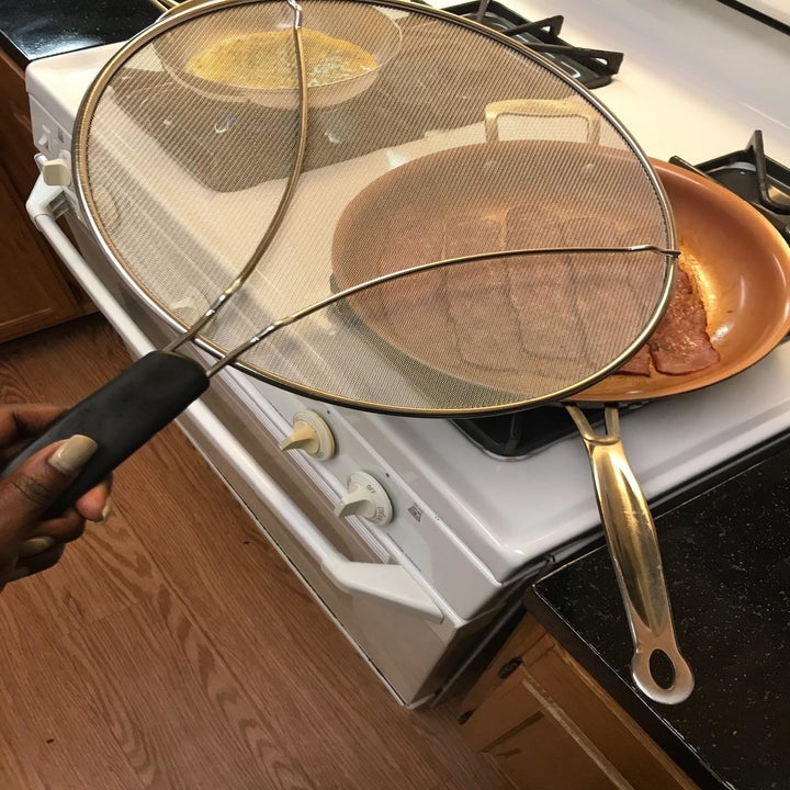 Reviewer holding splatter guard in front of frying pan