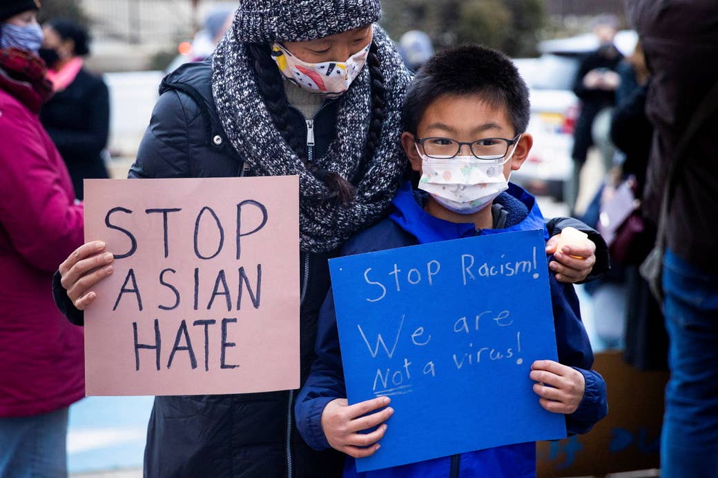 A mother and son at a rally against asian american violence hold signs that say &quot;stop asian hate&quot; and stop racsim! we are not a virus!&quot;