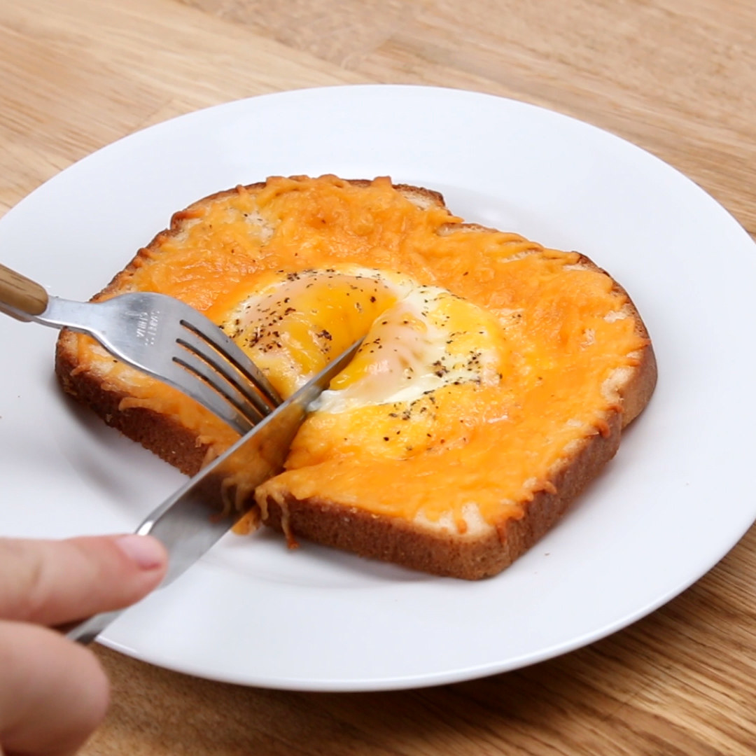 A person cutting into the toast with a knife and fork