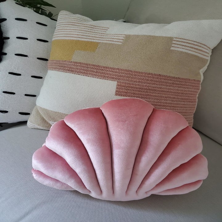 a reviewer's pink shell pillow on a couch