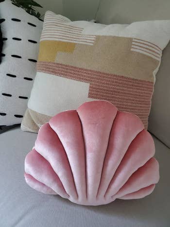 Reviewer's pink shell pillow on a couch