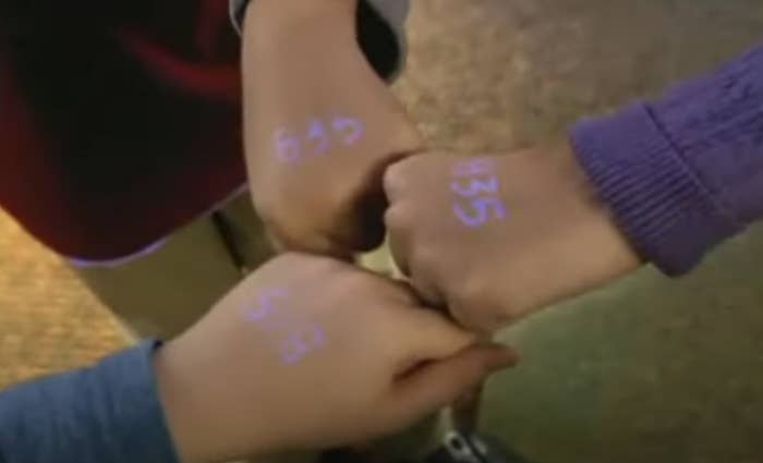 Children with glow in the dark number stamps on the backs of their hands