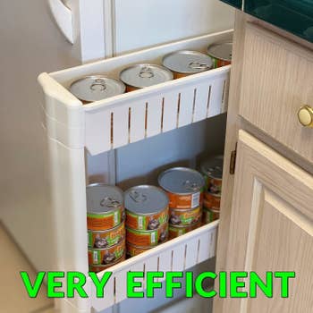 reviewer photo of a white storage unit holding cans of cat food sliding out from between a fridge and counter, with the text 