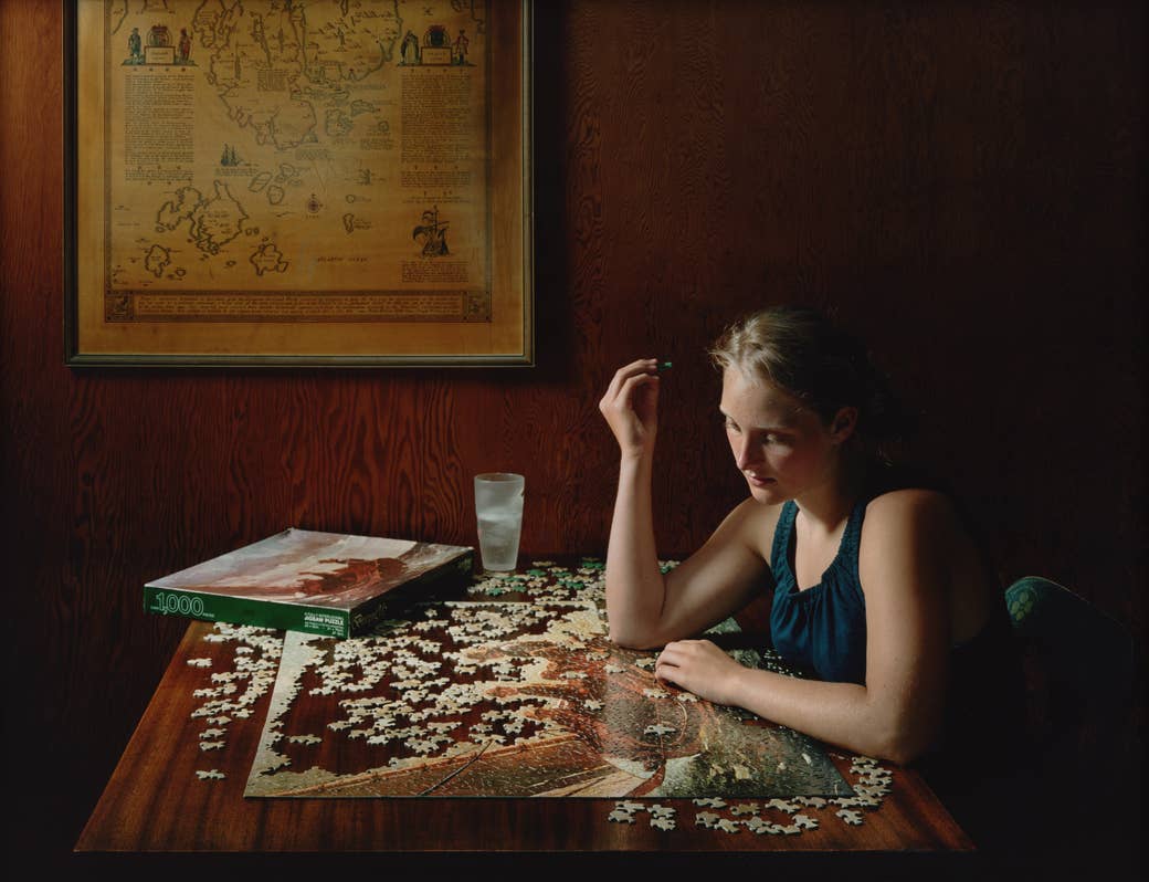 A woman playing with a puzzle in a wooden veneered room 