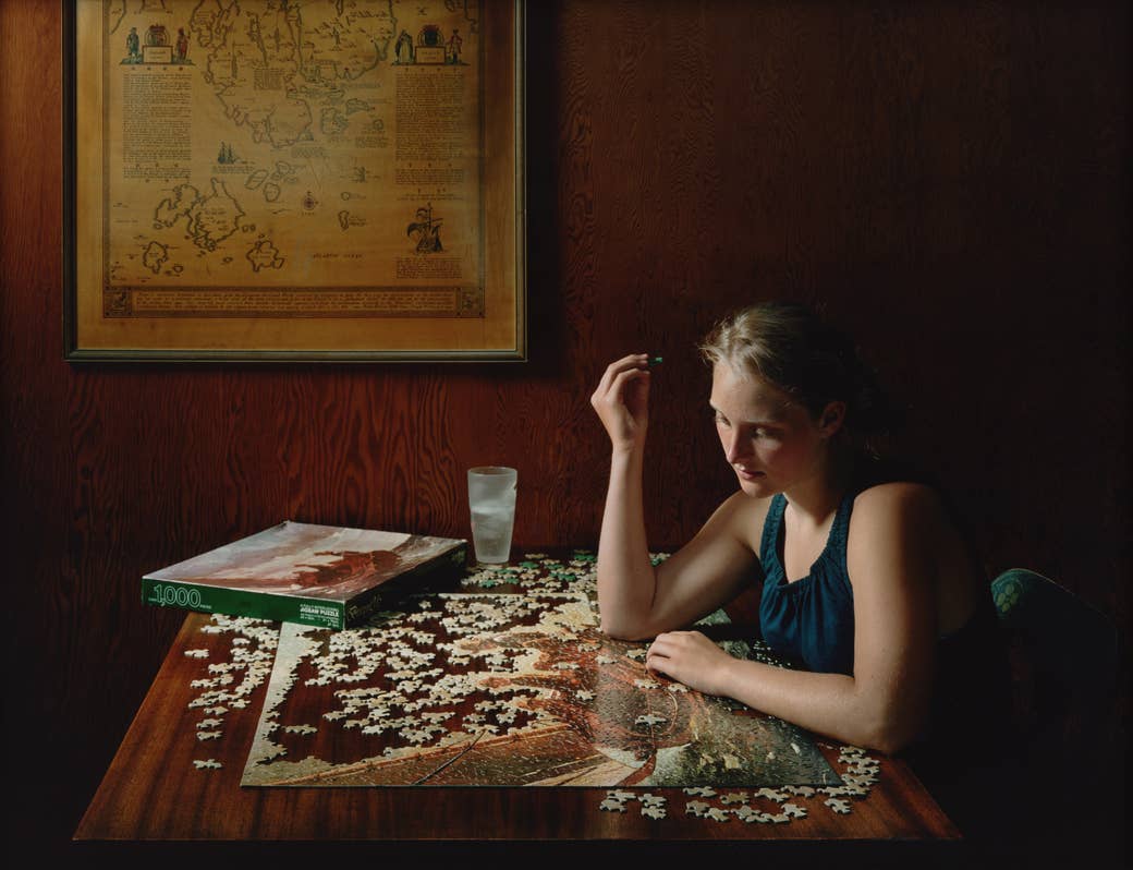 A woman playing with a puzzle in a wooden veneered room