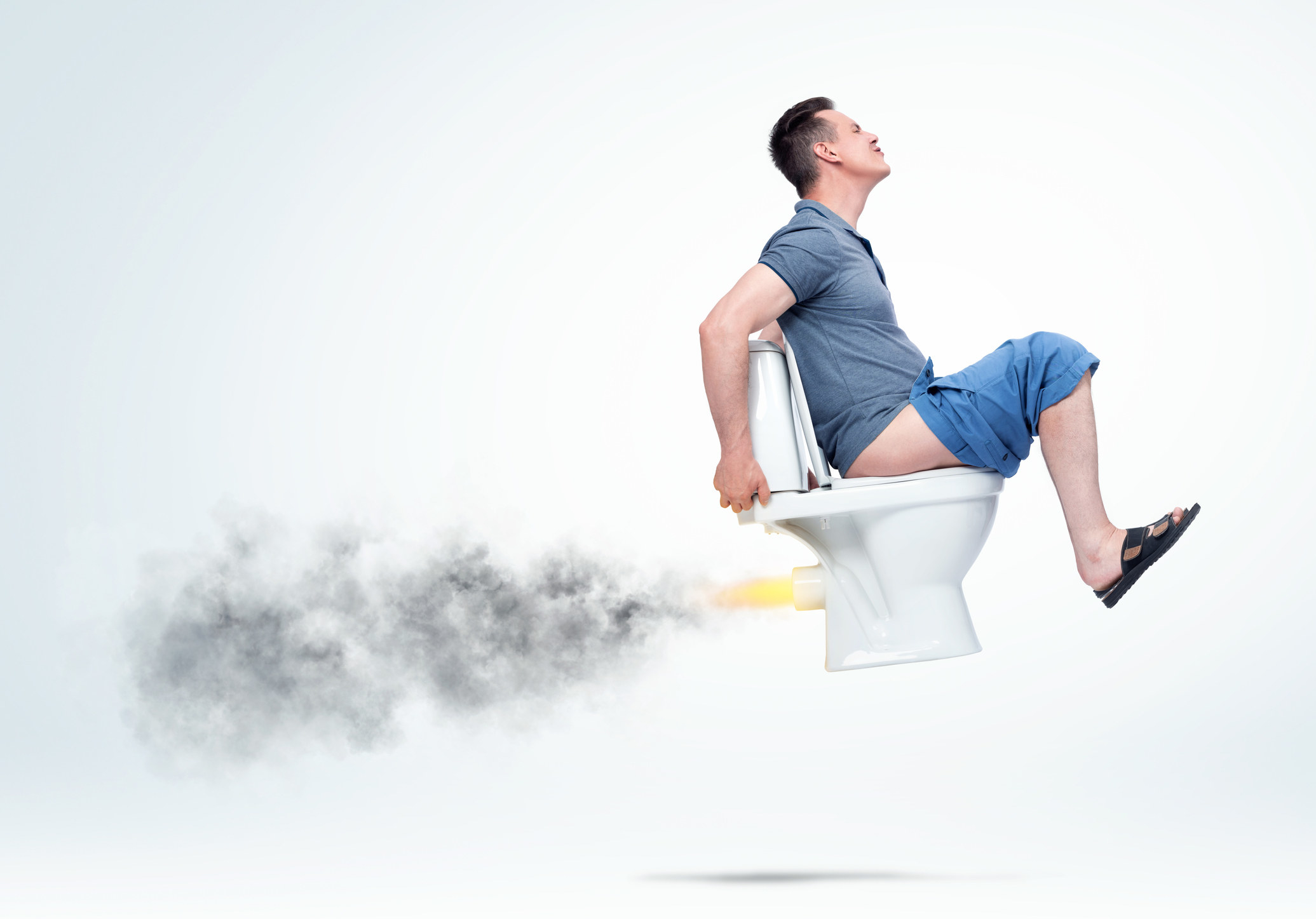 A man sitting on an airborne toilet in discomfort as smoke and fire comes out of the back