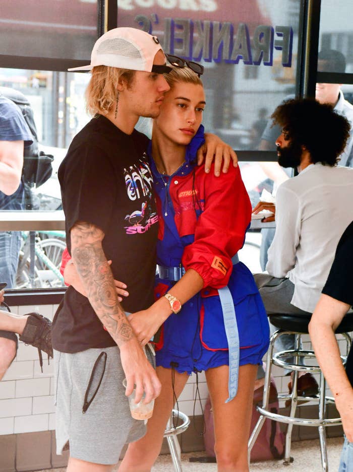 Justin and Hailey with their arms around each other at a restaurant
