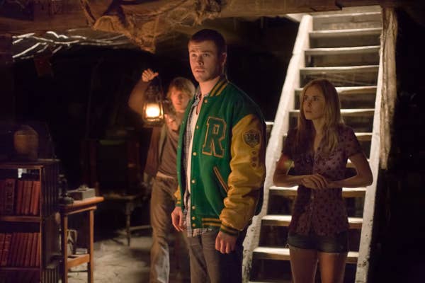 Curt standing in a basement in a Letterman jacket in The Cabin In The Woods