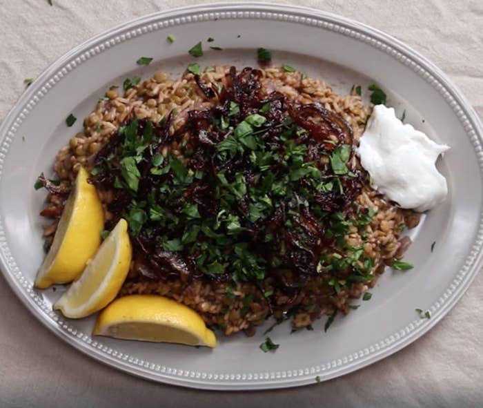 A platter of lentils and rice with caramelized onions, lemon wedges and Greek yogurt