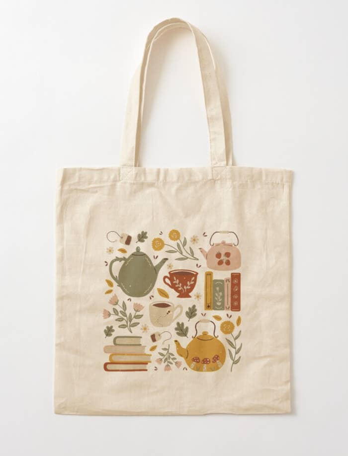 A vintage-style tote bag with whimsical illustration of teapots, teacups, plants, flowers, and books 