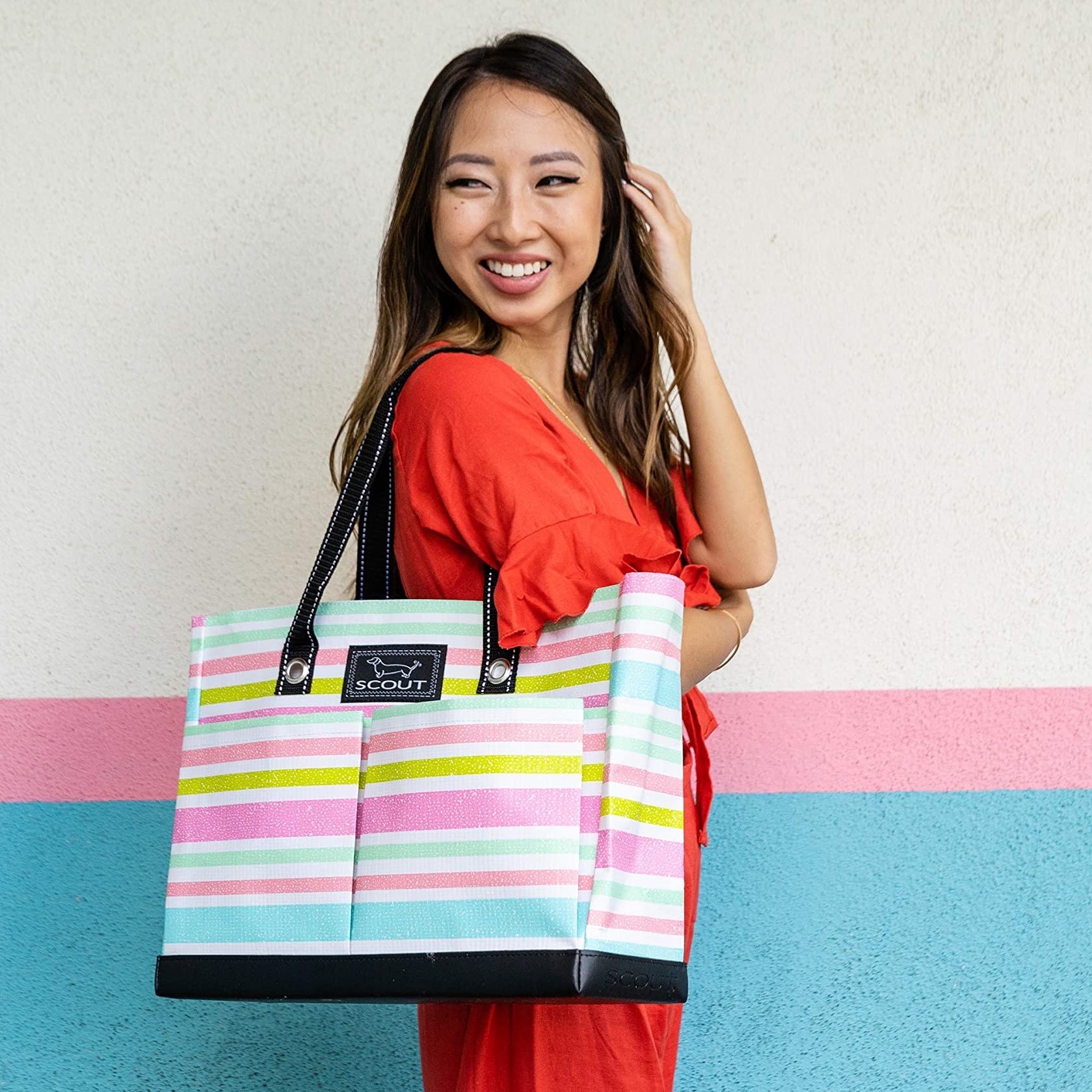 Model wearing the tote in light blue, pink, and gold stripes 