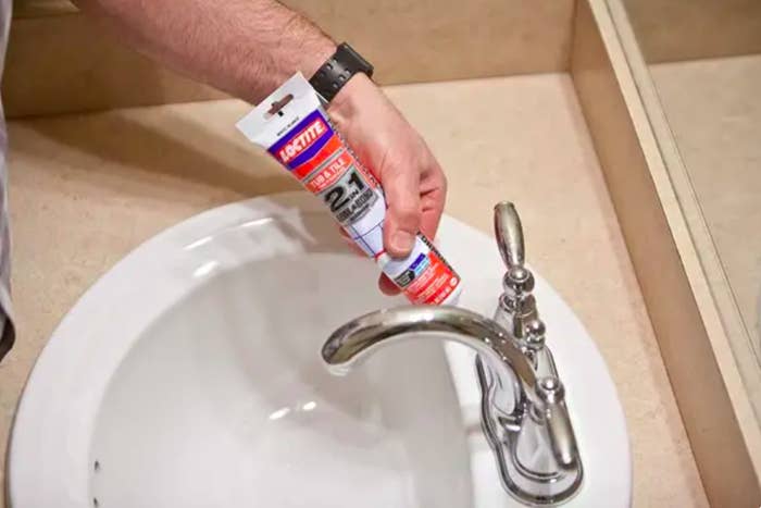 A person placing the sealant on a sink