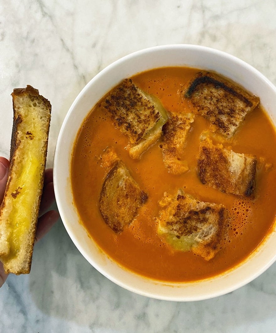A bowl of tomato soup with grilled cheese croutons.