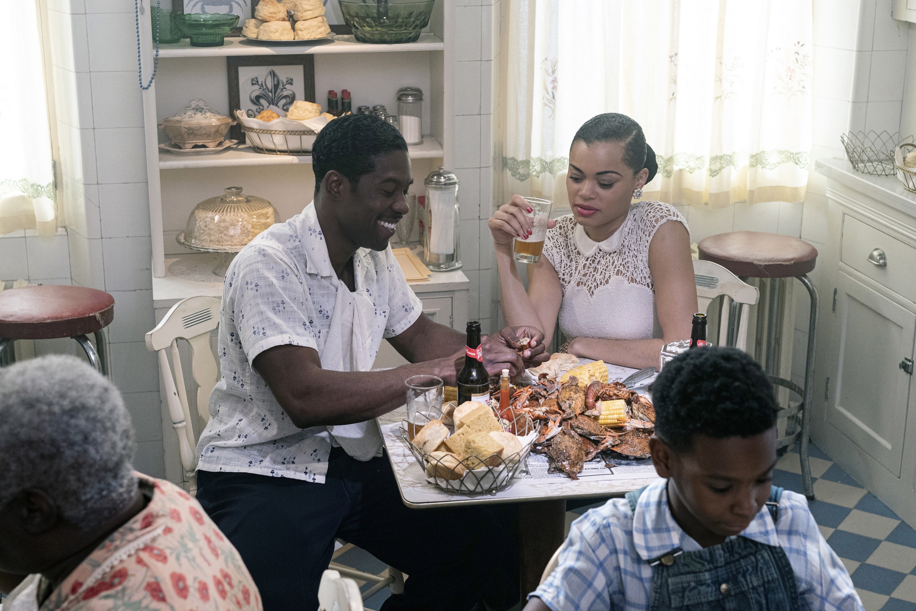 Trevante and Billie eating and drinking at a table in a scene from The United States Vs. Billie Holiday