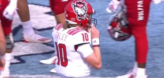 Red helmet with an oversize wolf head wearing an NC State cap