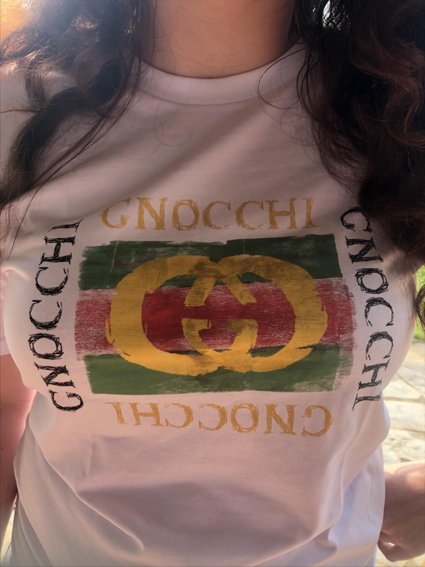 elizabeth wearing a white t-shirt reading &quot;gnocci&quot; in a gucci-like deisgn and font