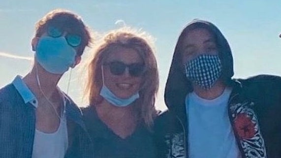 Britney smiles with her face mask down as she poses with her sons