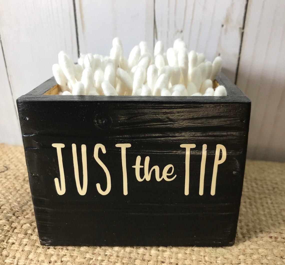 The wooden box filled with cotton swabs that reads &quot;JUST the TIP&quot;