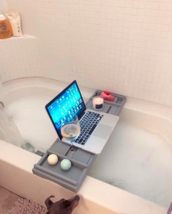 reviewer's bath caddy with a laptop wine and candle on it